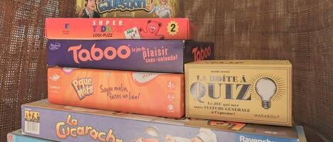 A stack of board games including Good Question!, Super Ted, Taboo, La Cucaracha, La Lote a Quiz, and Ravensburger.