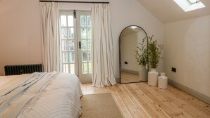 Quarto com cama, um espelho grande, um claraboia e uma planta em vaso.