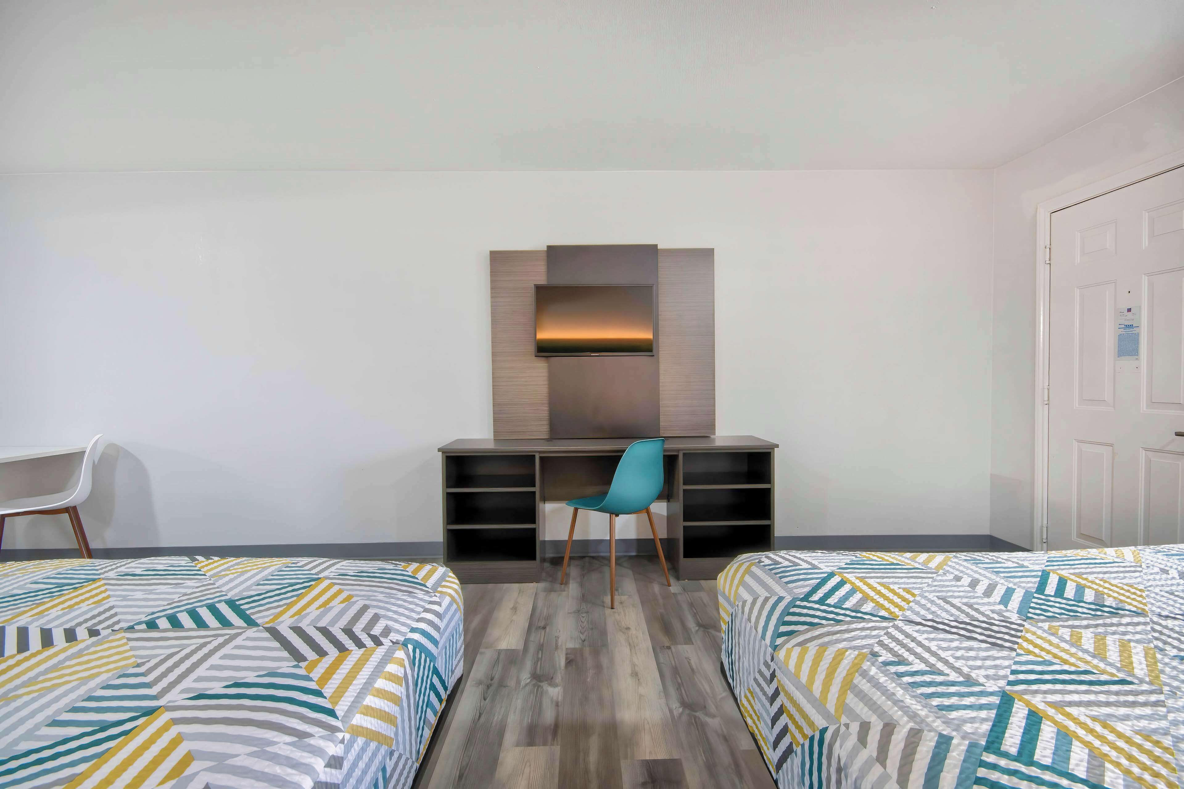 Una habitación con dos camas, un escritorio, una silla y un armario.