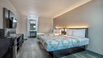 A hotel room with a bed, bedside table, TV, and a desk with a chair.