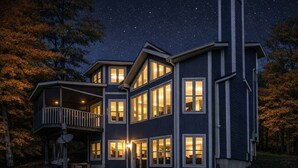Een meerlaags huis met een hottub in de voortuin, grote ramen en een balkon.