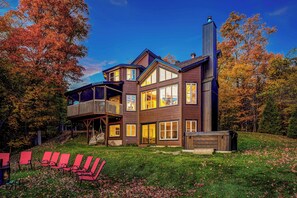 A multi-story house with a balcony, large windows, and a chimney.