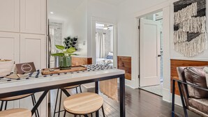 Un espace repas moderne avec une table en bois, quatre tabourets et un panneau d’accueil.