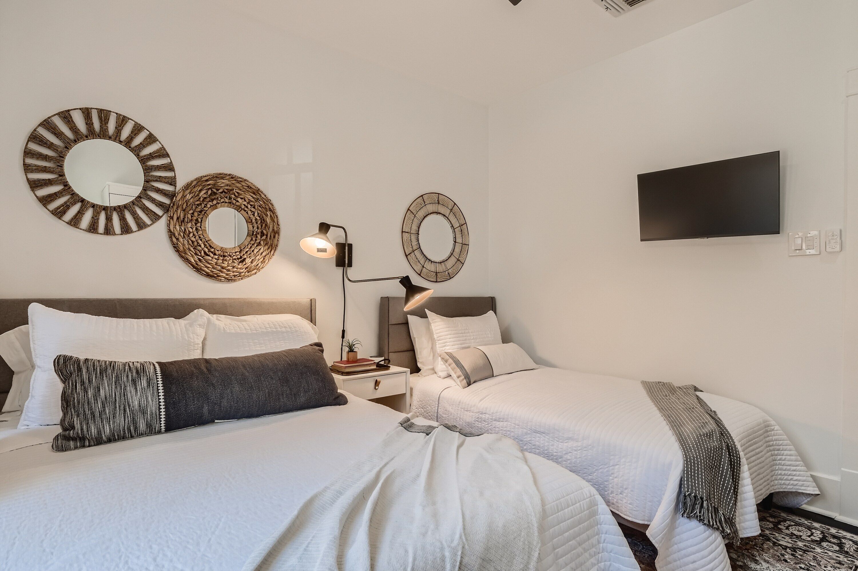 Une chambre d’hôtel avec deux lits, un téléviseur à écran plat et des miroirs décoratifs sur les murs.