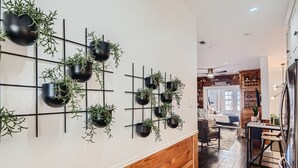 Un salon moderne avec un banc en bois, un coin repas avec une table et une cuisine équipée d’un réfrigérateur.