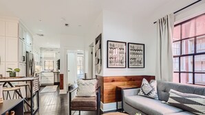Un salon moderne avec un canapé gris, un mur d’accent en bois et des œuvres d’art encadrées.