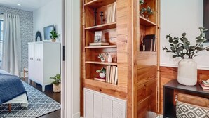 Une chambre moderne avec une bibliothèque en bois, une armoire blanche et un tapis à motifs.