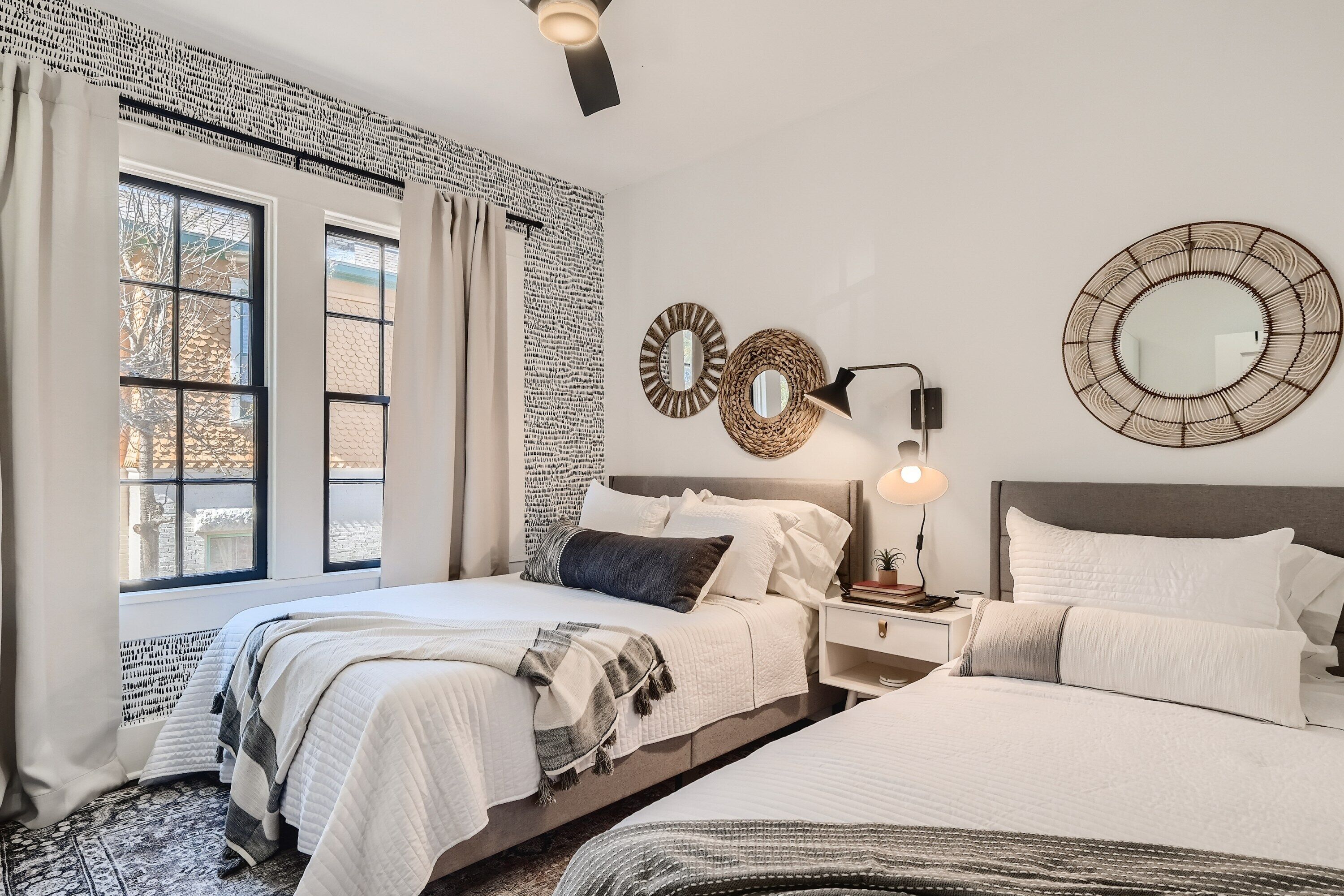 A modern bedroom with a large bed, bedside tables, and a wall-mounted mirror.