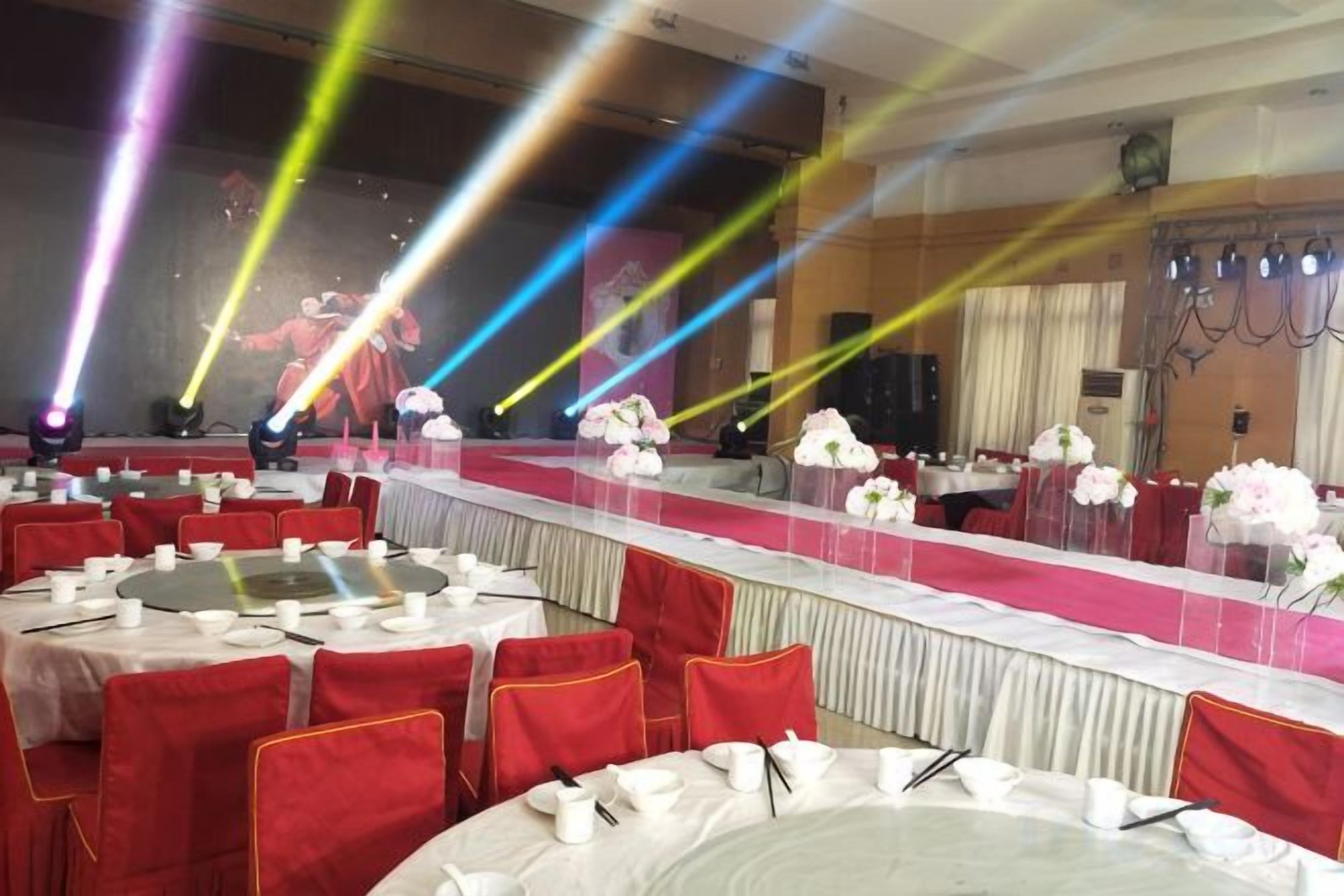 A banquet hall with round tables, red chairs, and white tablecloths.