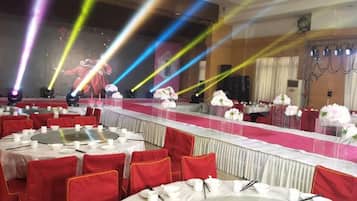 A banquet hall with round tables, red chairs, and white tablecloths.