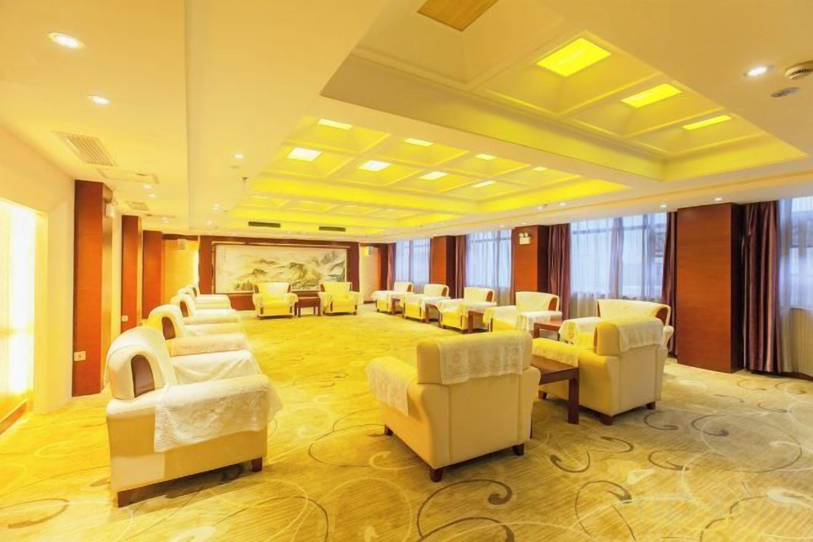 A hotel room with a large seating area, a dining table, and a view of the city.