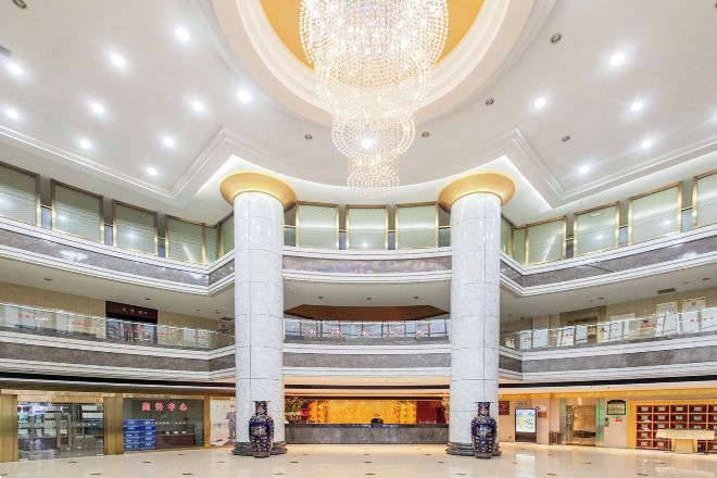 A multi-level atrium with a central chandelier, multiple floors, and a variety of shops and services.