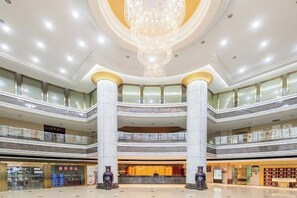 A multi-level atrium with a central chandelier, multiple floors, and a variety of shops and services. - Dabieshan Hotel (Luotian County)