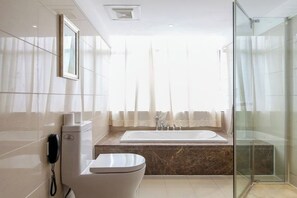 Un baño moderno con inodoro, lavamanos, bañera y cabina de ducha de cristal.