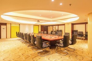Une salle de conférence dotée d’une longue table et de nombreuses chaises, d’un écran de projection et d’un sol recouvert de moquette.