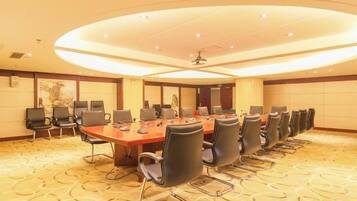 A conference room with a long table, multiple chairs, and a carpeted floor.