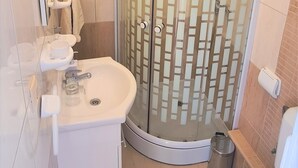 Un baño moderno con ducha de vidrio, un lavamanos con espejo y un inodoro.