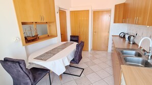 Una cocina compacta con armarios de madera, un lavamanos y una zona de comedor con mesa y sillas.
