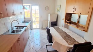Una cocina compacta con lavabo, estufa y comedor con mesa y sillas.