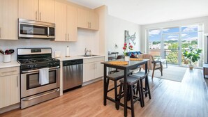 Une cuisine moderne dotée d’appareils électroménagers en acier inoxydable, de meubles en bois et d’un coin repas offrant une vue sur la ville.