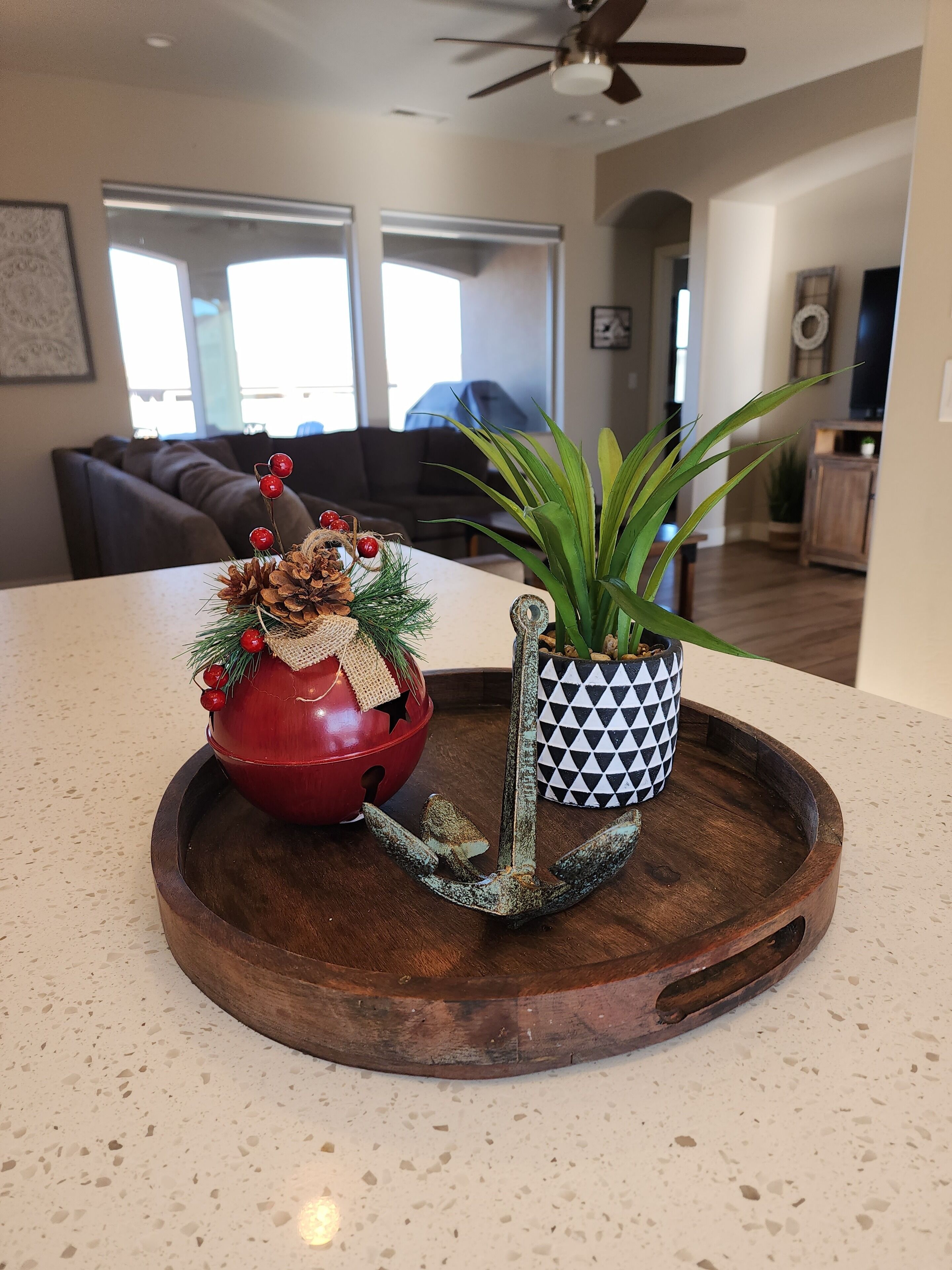 A wooden tray with a red decorative bowl and a potted plant on a kitchen counter.