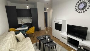 Een moderne woonkamer met een bank, televisie en decoratieve klok.