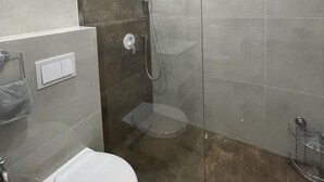 Een moderne badkamer met een douchecabine van glas, een toilet en een handdoekhouder.
