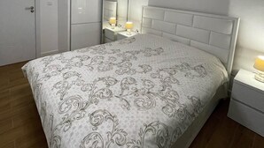 Een slaapkamer met een bed, nachtkastjes, een spiegel en een plafondlamp.