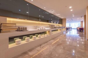 Un moderno vestíbulo de hotel con una larga recepción, una estación de café y un área de descanso.
