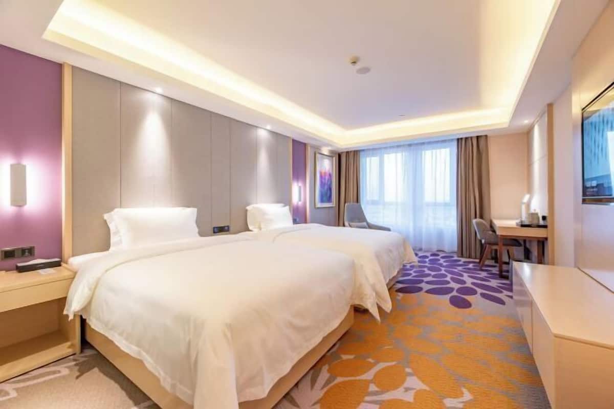 A hotel room with two beds, a desk, and a chair.