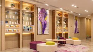 A modern lobby with round seating, glass display shelves, and abstract wall art. - Lavande Hotel (Heze Daxue Road Branch) (Heze)