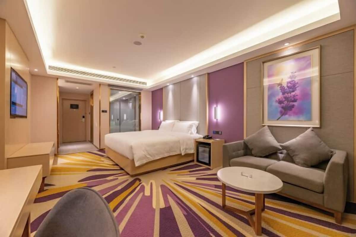 A hotel room with a bed, a sofa, a coffee table, and a TV.