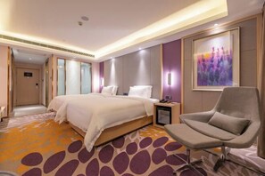A hotel room with a large bed, a chair, a nightstand, and a painting on the wall. - Lavande Hotel (Heze Daxue Road Branch) (Heze)