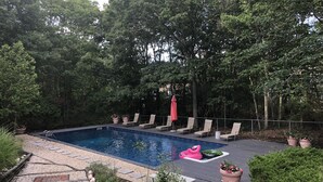 Una piscina con sillas de descanso y plantas en macetas.