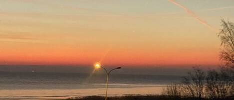 Ein Sonnenuntergang über einem Gewässer, mit einer Straßenlaterne und weiter Ferne.