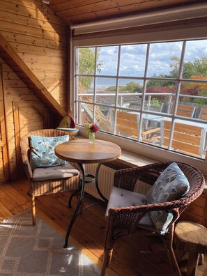 A cozy room with a wooden interior, a large window, wicker furniture, and a view of the outdoors. - Thatched-roof vacation home with a view of the water, a garden, and a fireplace (Stahlbrode)
