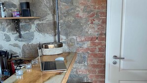 Un coin cuisine avec un plan de travail en bois, un ordinateur portable, une machine à café et un mur en briques.