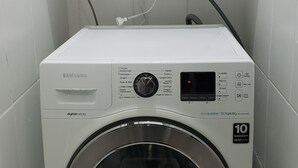 A Samsung digital inverter washing machine in a small laundry room with a shelf above containing cleaning supplies. - Apto. Completo Prox a av. Paulista (São Paulo)