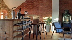 Een keuken met een bakstenen muur, houten keukenkastjes en barstoelen.