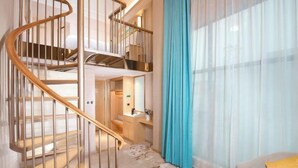 Un intérieur moderne avec un escalier en colimaçon, un canapé et une petite table sur laquelle se trouve une tasse.