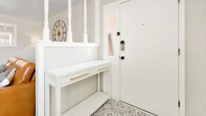 Une pièce avec une console blanche, un canapé en cuir marron et un sol à motifs.