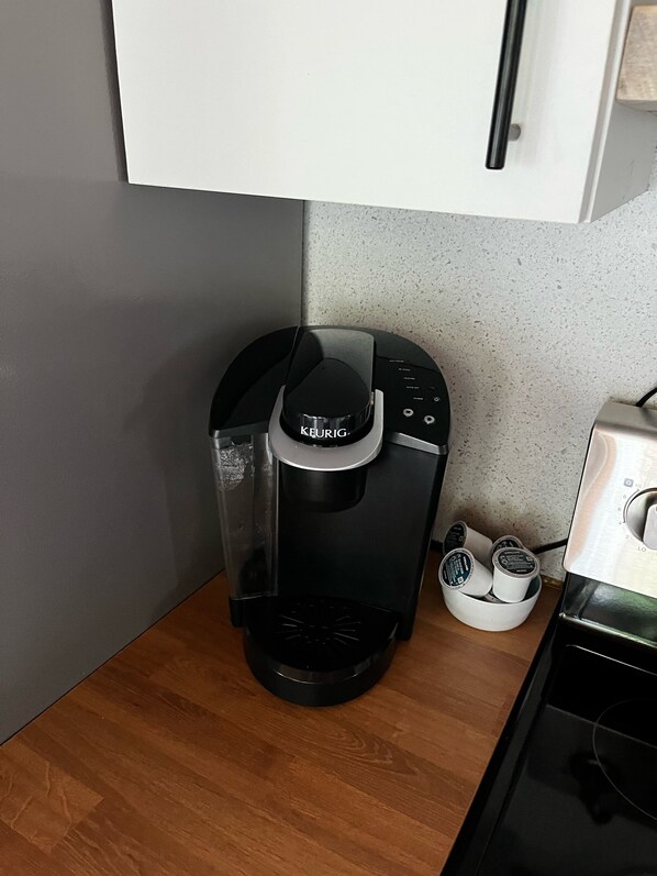 Una cafetera Keurig sobre una encimera de cocina, con un soporte para cápsulas de café cerca.