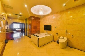 Bathroom features a large bathtub, vanity area with sink and mirror, and a mounted television.