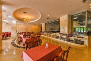 Ein Restaurant mit runden Tischen, einer Theke in der Mitte und Blick durch große Fenster.
