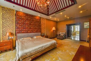 Relax in comfort with a large bed, nightstand, and table, surrounded by a patterned wall and decorative ceiling.