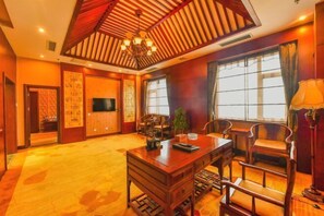 Une chambre traditionnelle avec un bureau en bois, des chaises, une télévision et de grandes fenêtres.