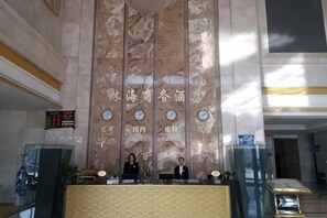 A reception desk with a marble wall, clocks, and a sign with Chinese characters. - Linhai Business Hostel (Luannan)