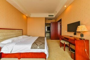 A hotel room with a bed, a desk, a chair, a television, and a lamp. - Linhai Business Hostel (Luannan)