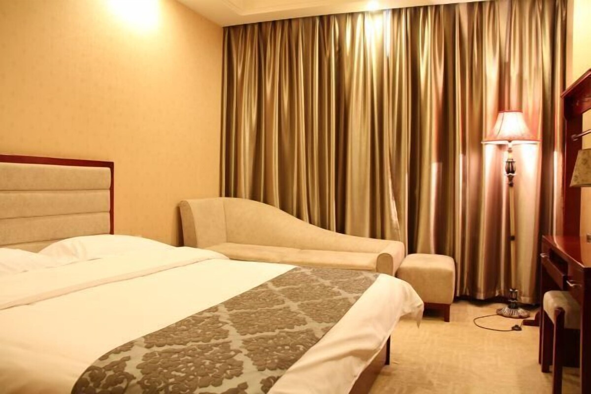 Une chambre d’hôtel avec un lit, un canapé, un bureau et une lampe.