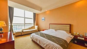 Habitación de hotel con cama, escritorio, silla, mesita de noche y ventana con cortinas.